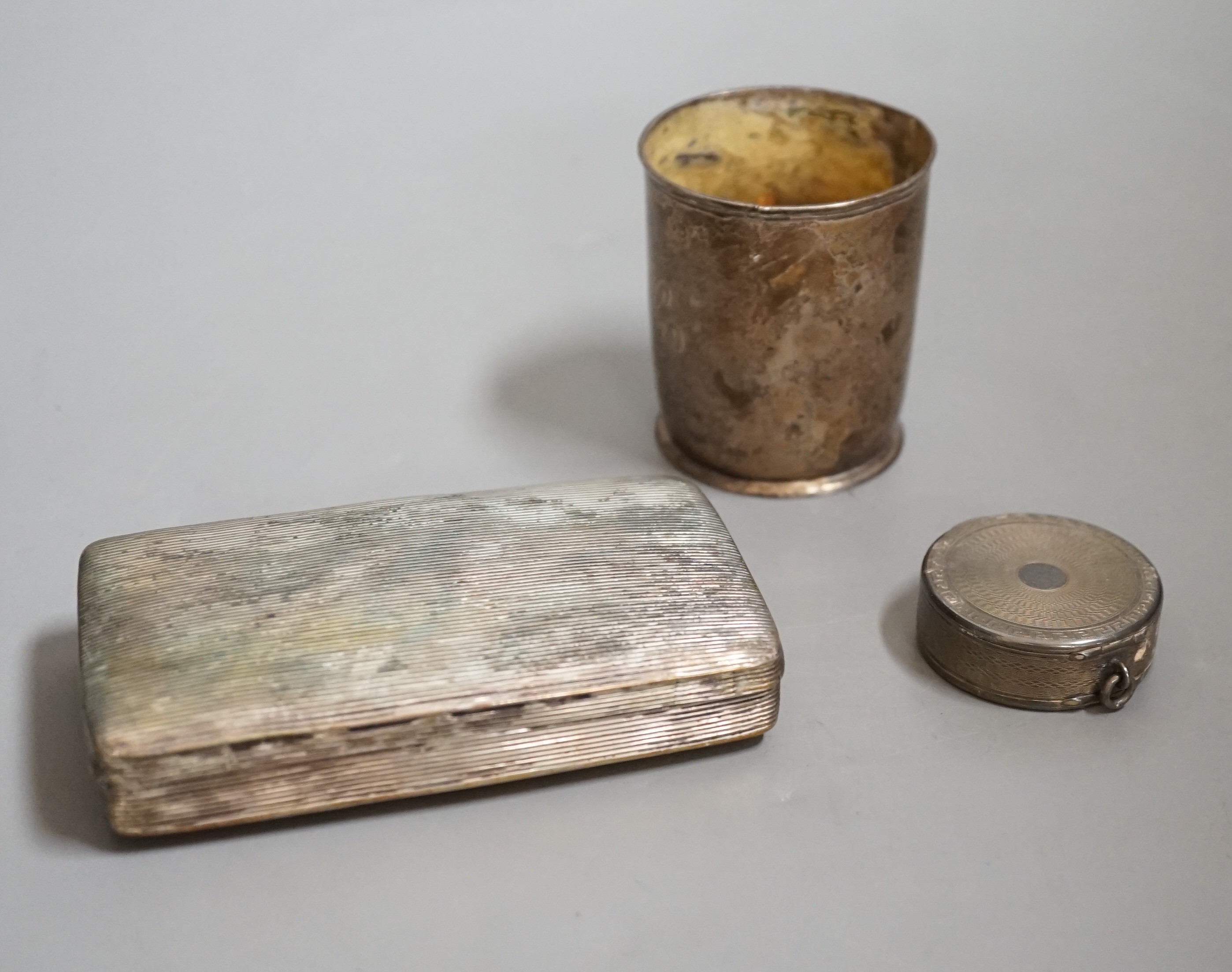 A Dutch white metal tobacco box, 11.3cm and a similar beaker (both a.f.) together with a French engine turned white metal circular compact.